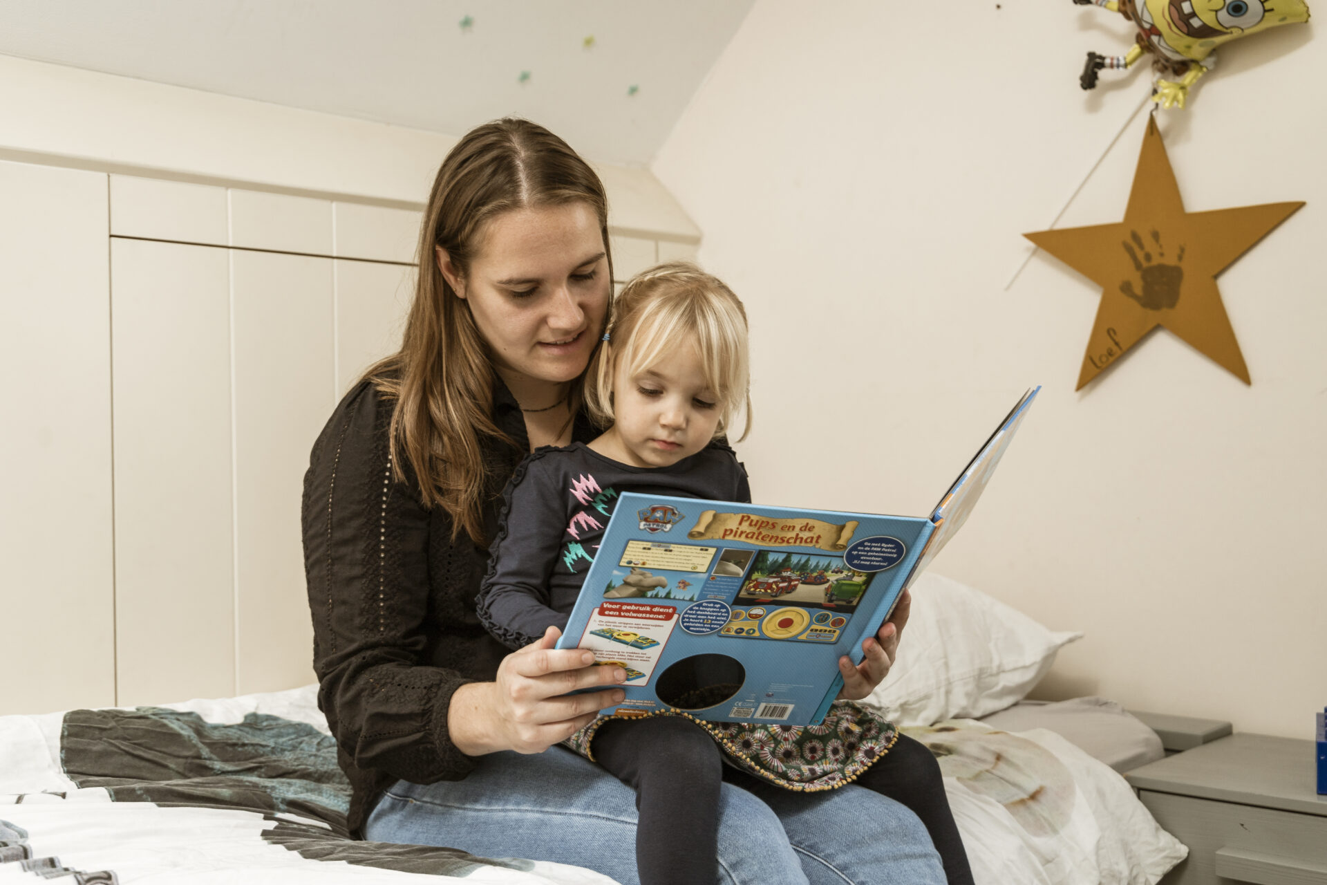 Moeder leest samen met haar dochter een prentenboek op bed, een knus voorleesmoment vol aandacht en plezier
